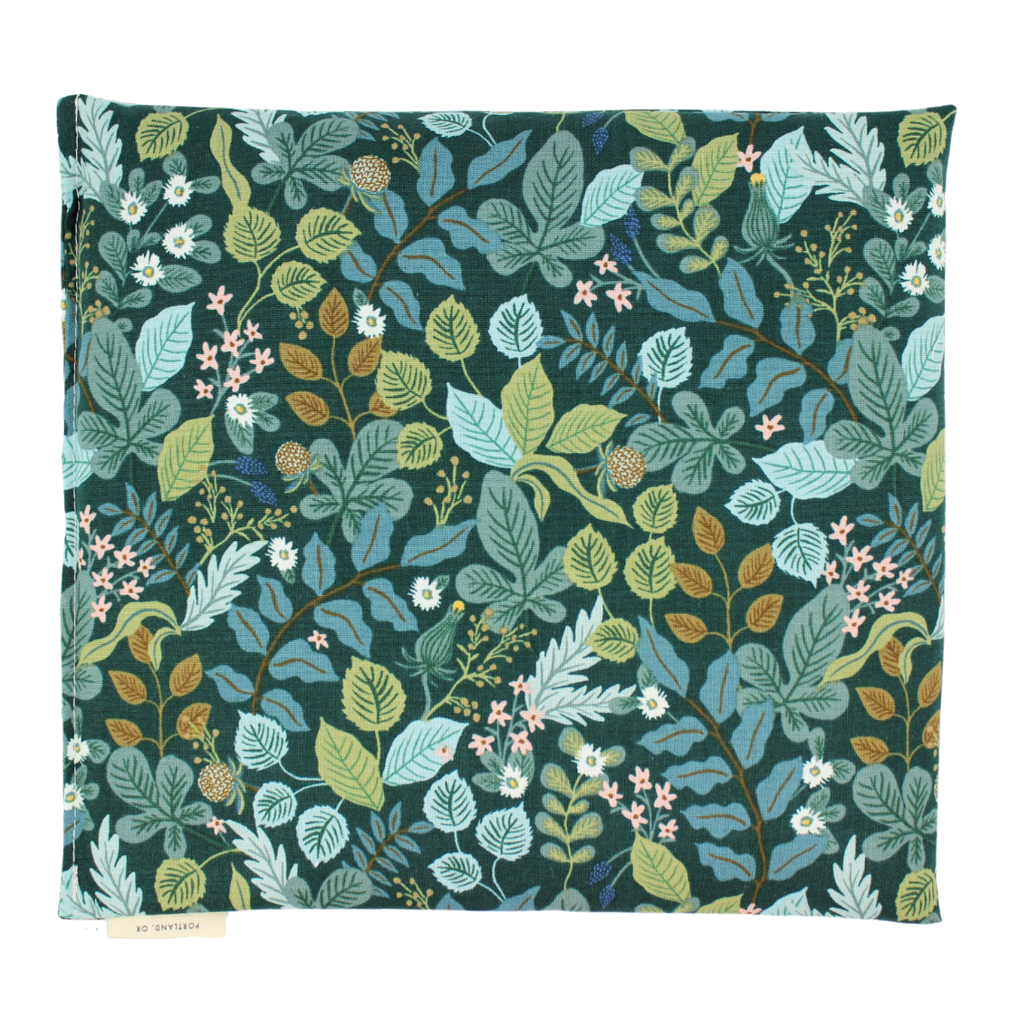 Small hot or cold aromatherapy wrap featuring an intricate botanical pattern with leaves and small flowers in shades of teal, sage green, light blue, olive, and pink on a dark green background. A small fabric brand tag is visible on the bottom left edge.