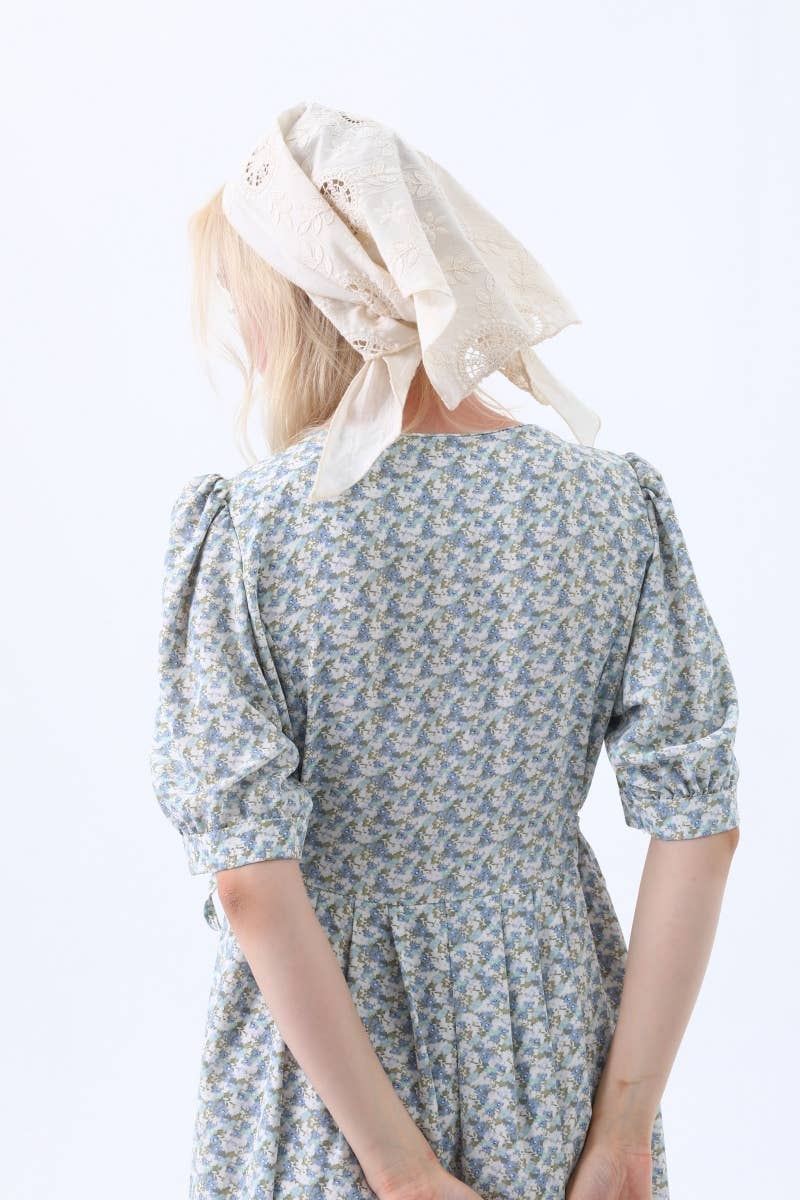Person wearing a floral dress with a white headscarf on a light background