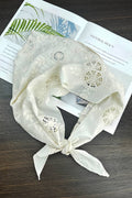 White lace scarf with floral patterns on a wooden surface