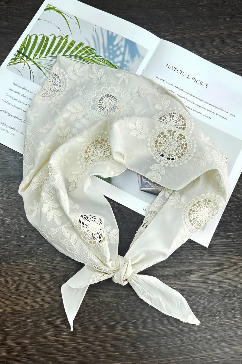 White lace scarf with floral patterns on a wooden surface