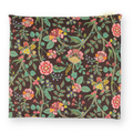 Small patterned hot or cold aromatherapy wrap with botanical pattern with pink, yellow, and green flowers and leaves on a dark brown background. A small cream-colored fabric tag is visible on the top right edge.
