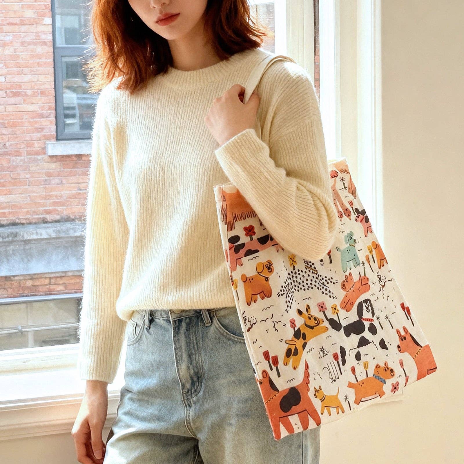 Person holding a patterned bag with dog designs indoors.