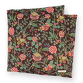 Large aromatherapy hot or cold wrap featuring a dense, colorful floral pattern on a dark brown background, shown with a second folded pillow behind it on a clean white background.