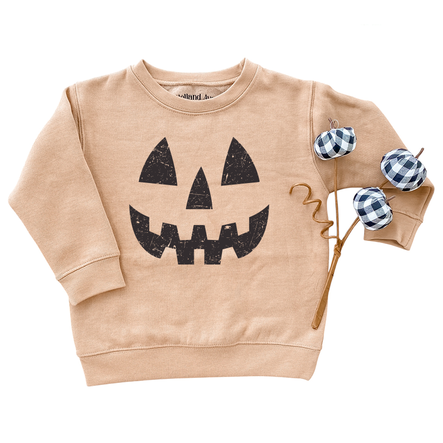 Beige sweatshirt with black jack-o'-lantern face design on a white background