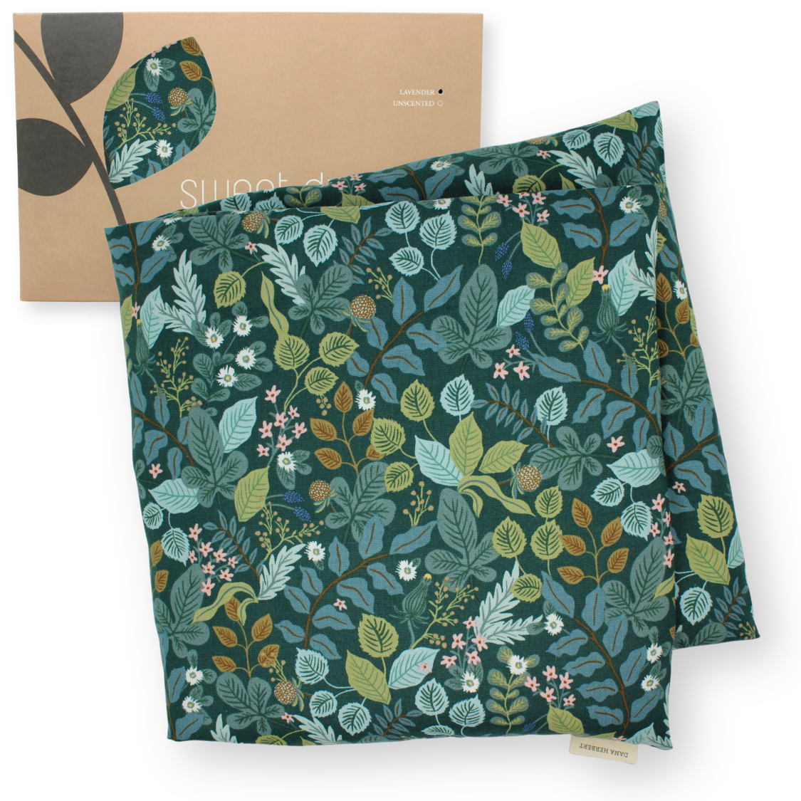 Large aromatherapy hot or cold wrap with an all-over botanical leaf print in teal, green, and blue tones, shown with a kraft paper sleeve or box featuring a matching leaf motif on a white background.