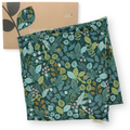 Large aromatherapy hot or cold wrap with an all-over botanical leaf print in teal, green, and blue tones, shown with a kraft paper sleeve or box featuring a matching leaf motif on a white background.