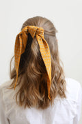 Woman with long hair wearing a yellow patterned headscarf on a white background