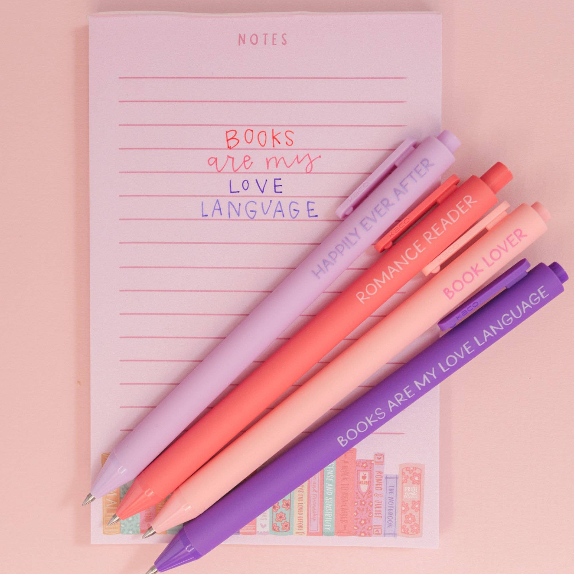 Colorful pens on a notebook with text on a pink background