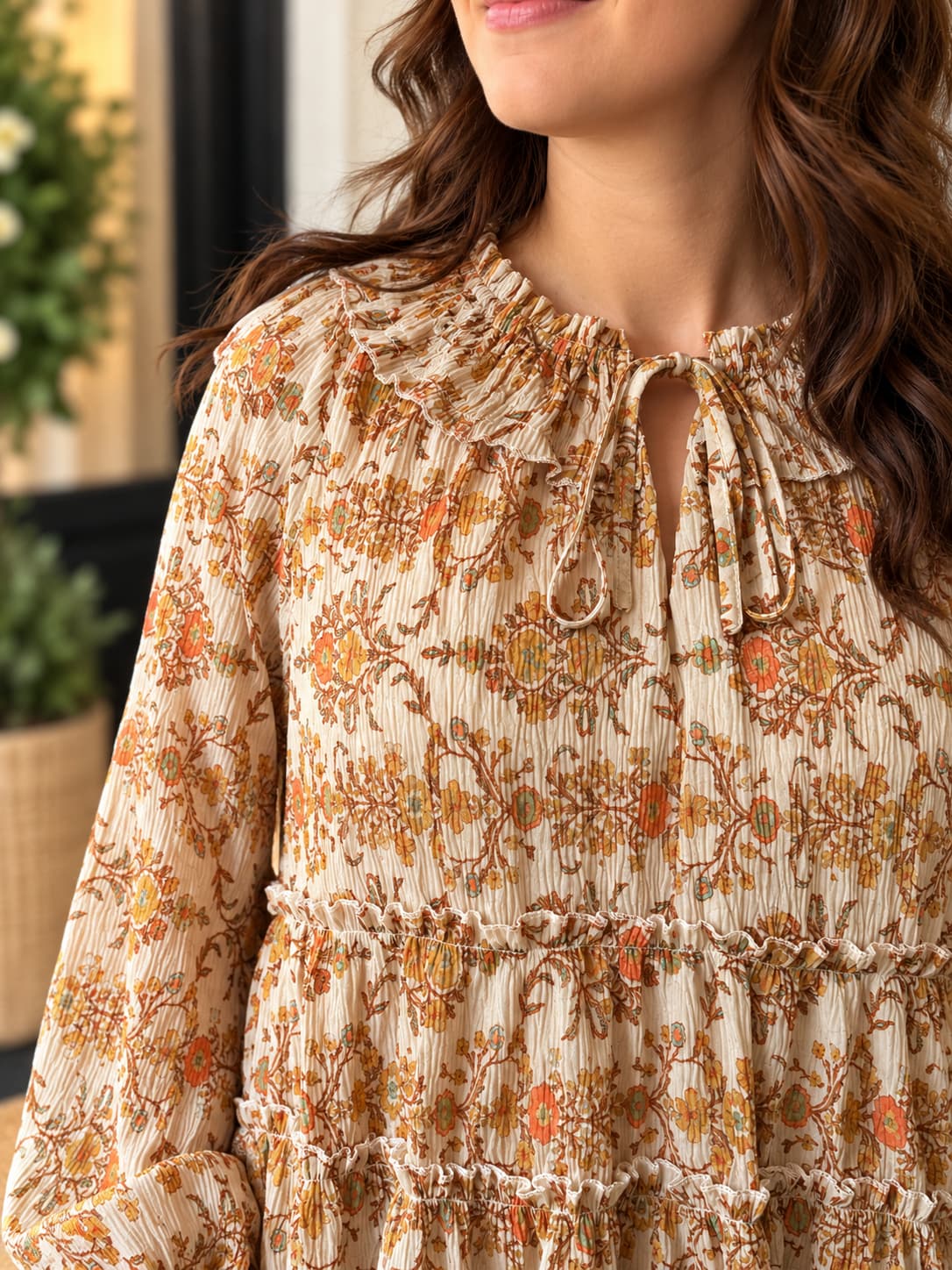 Close up of woman wearing printed boho style peasant blouse top in beautiful orange and tan colors.