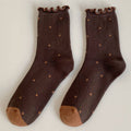 Pair of brown socks with ruffled top and polka dot pattern on a light gray background