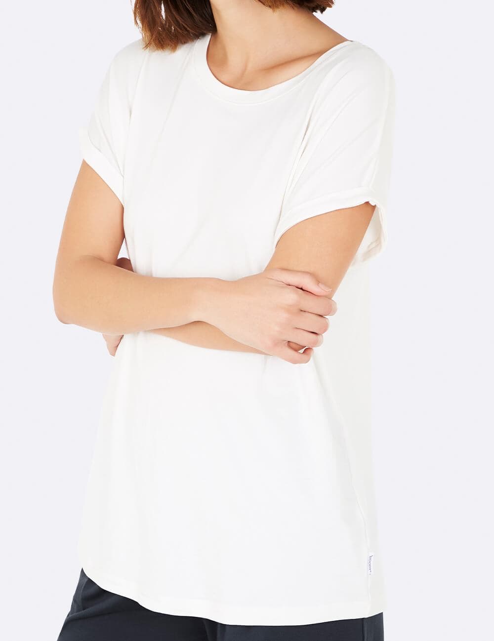 A woman wearing a plain white short-sleeve crewneck t-shirt, shown from the shoulders down against a clean white background.
