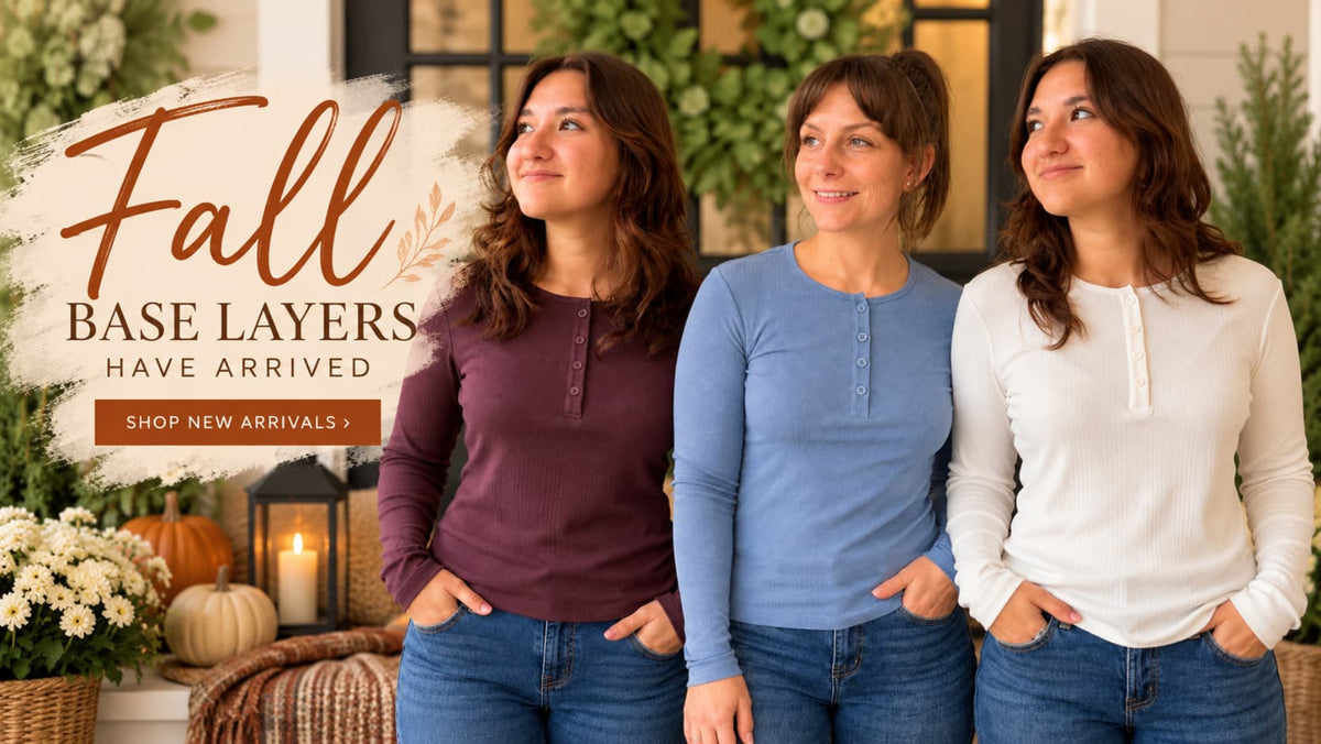 Three women wearing long-sleeve henley base layer tops in maroon, dusty blue, and white, standing together in a cozy fall-themed setting with pumpkins, candles, and a 'Fall Base Layers Have Arrived' promotional graphic.