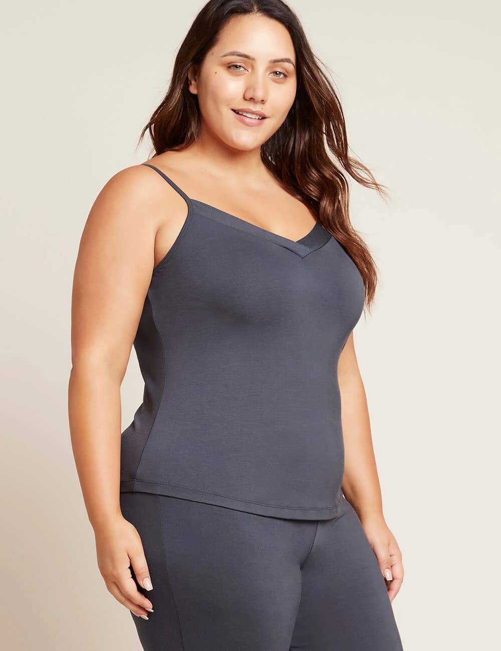 Woman wearing a dark gray tank top and leggings on a beige background