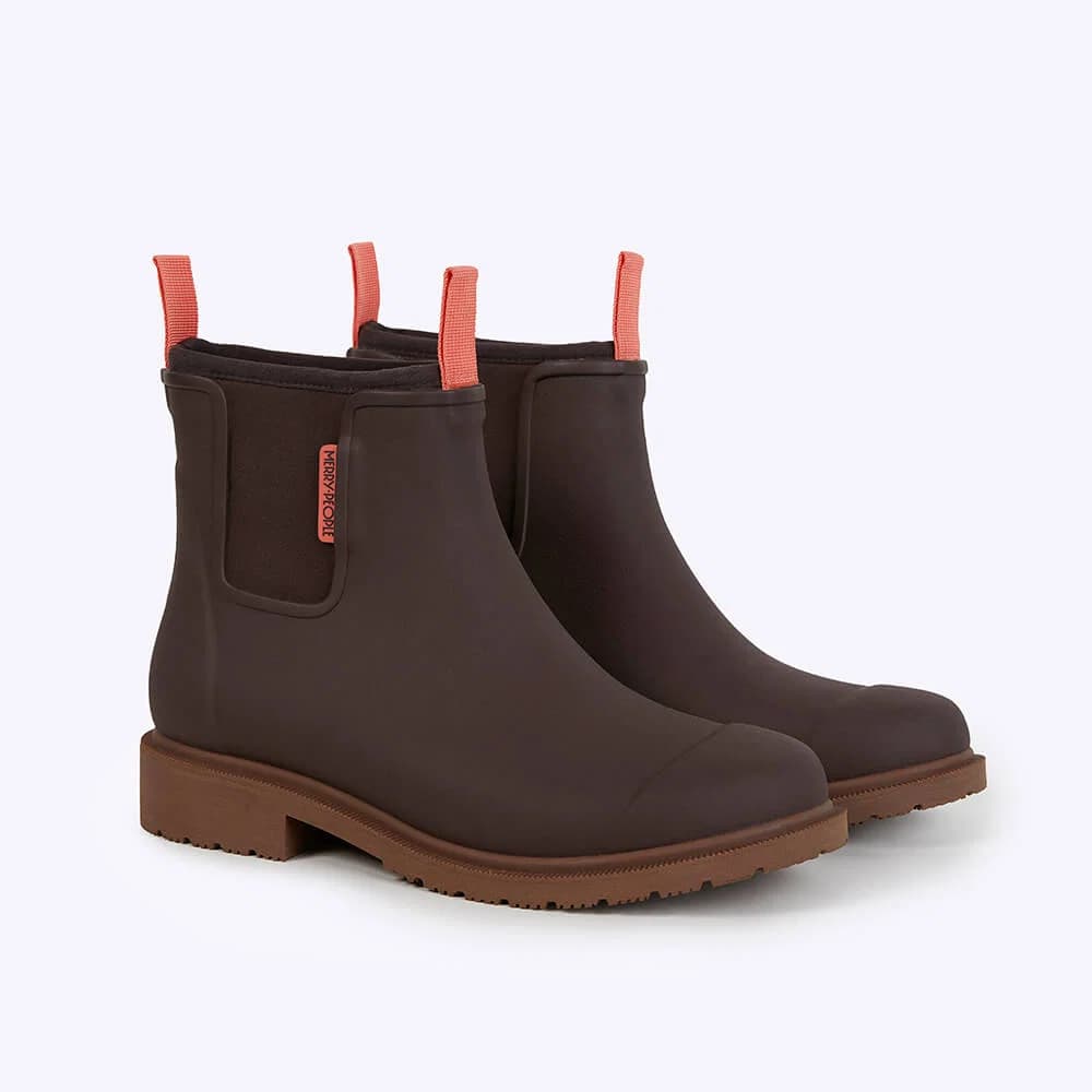 A pair of dark brown gum rain boots with bright coral orange pull tabs and a small orange 'MERRY PEOPLE' brand tag on the side, set against a clean white background.