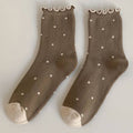 Pair of brown socks with white polka dots on a light gray background