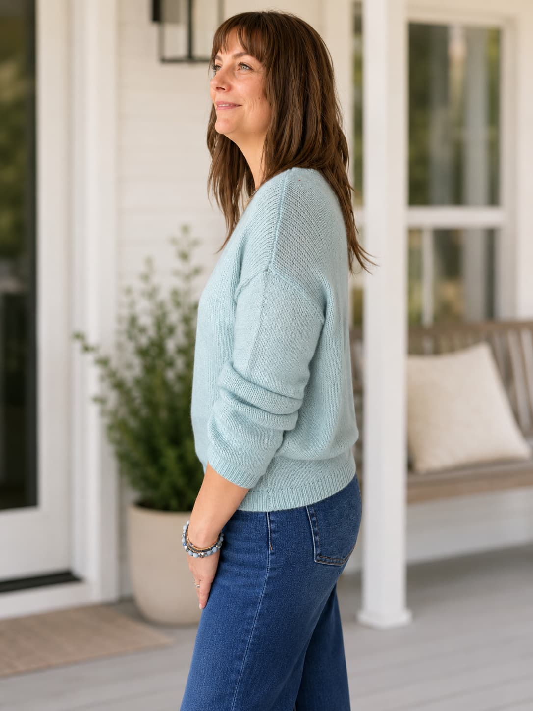 A woman wearing a light blue knit sweater and blue jeans perfect for fall transition.