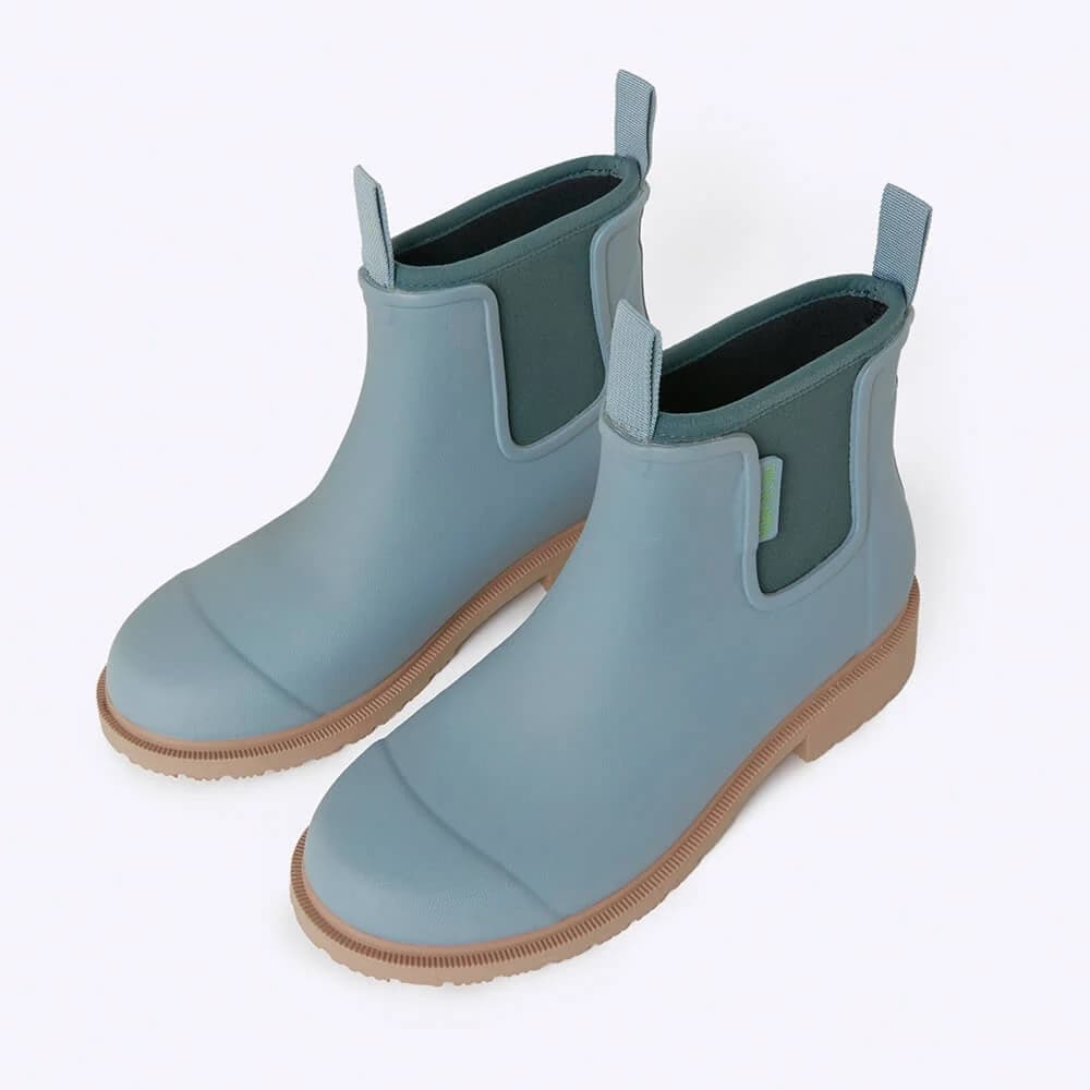 Pair of light blue rubber boots with brown soles on a white background