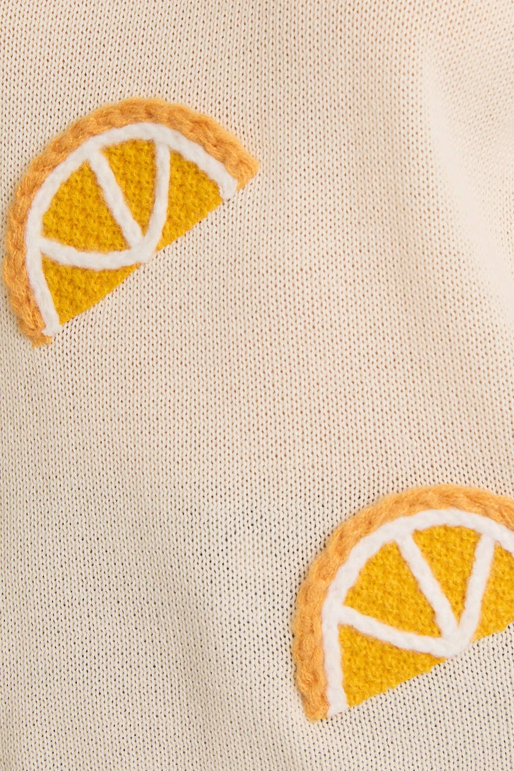 Two embroidered orange slices on a beige fabric background