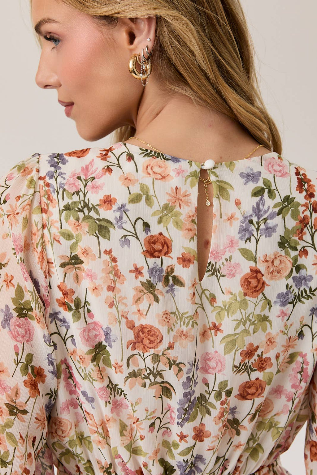 Woman wearing a long sleeve floral dress with key hole back detail.