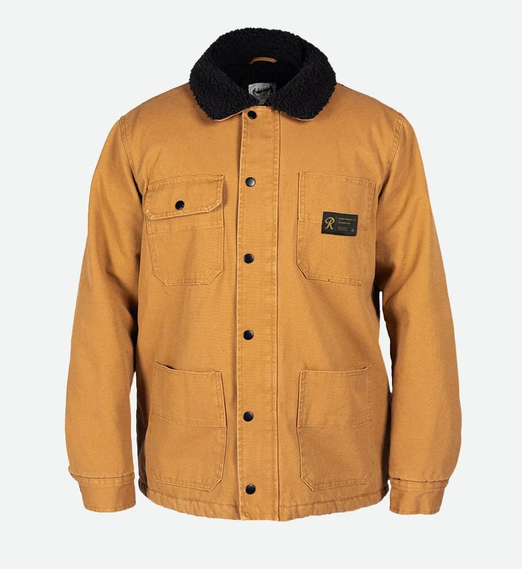 A Carhartt waxed canvas utility jacket in a warm camel/tan color, featuring a black sherpa fleece collar, black snap-button front closure, two chest flap pockets, and a black Carhartt brand patch on the left chest.