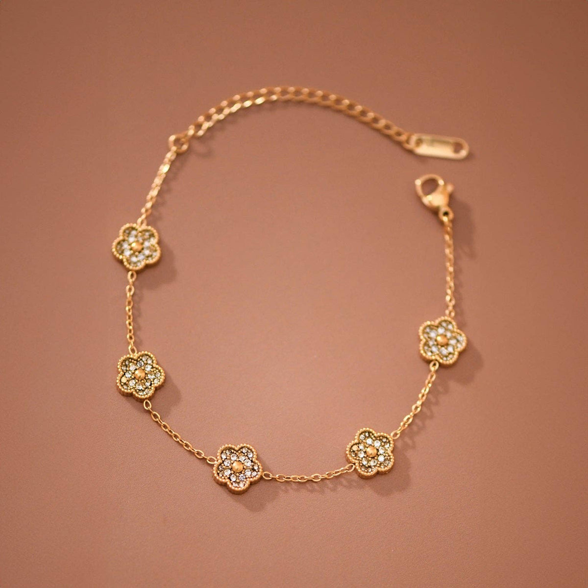 Gold bracelet with floral designs on a brown background