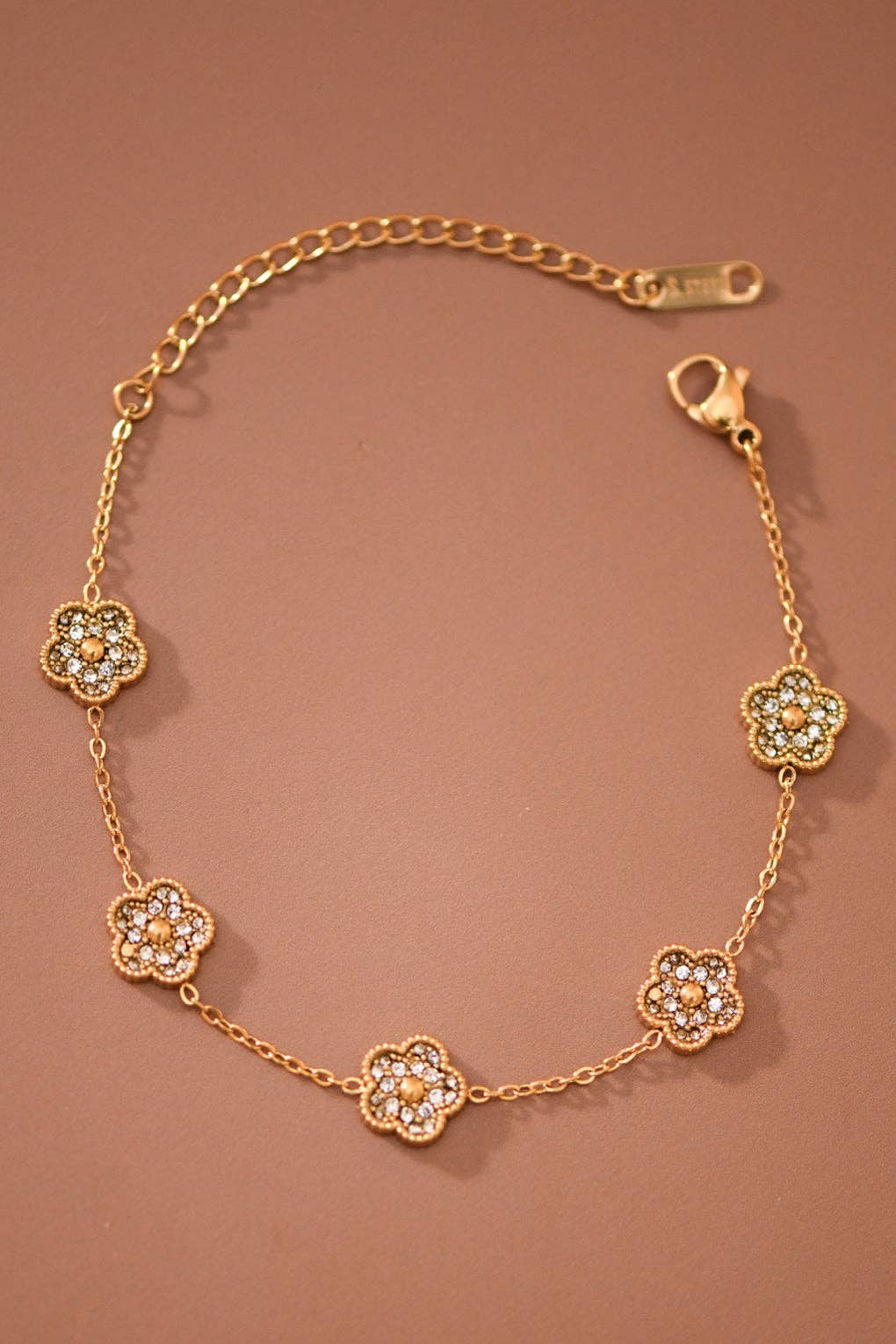 Gold bracelet with floral designs on a brown background