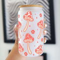 Tumbler with mushroom pattern held by a hand against a blurred background