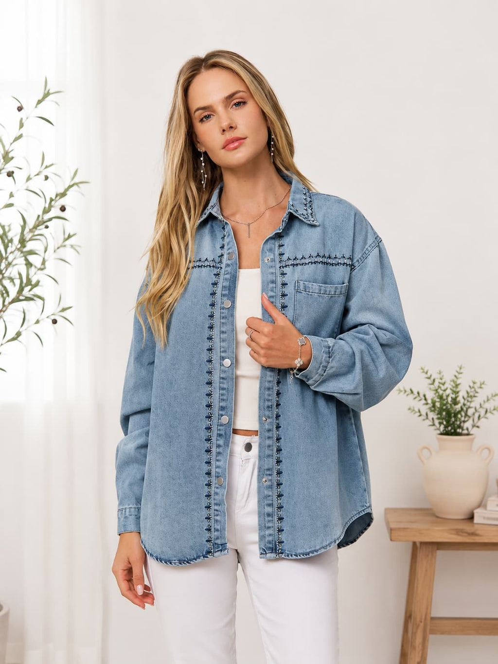 Woman wearing embroidered shirt jacket with white tank and white pants.