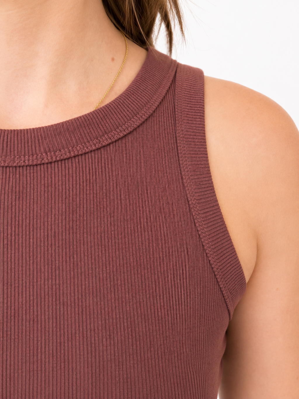 Close-up of a ribbed knit sleeveless top in a muted dusty rose or mauve color, worn by a model against a plain white background.