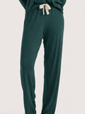 Dark green lounge pants with a cream-colored drawstring tie, shown on a model against a light gray studio background.