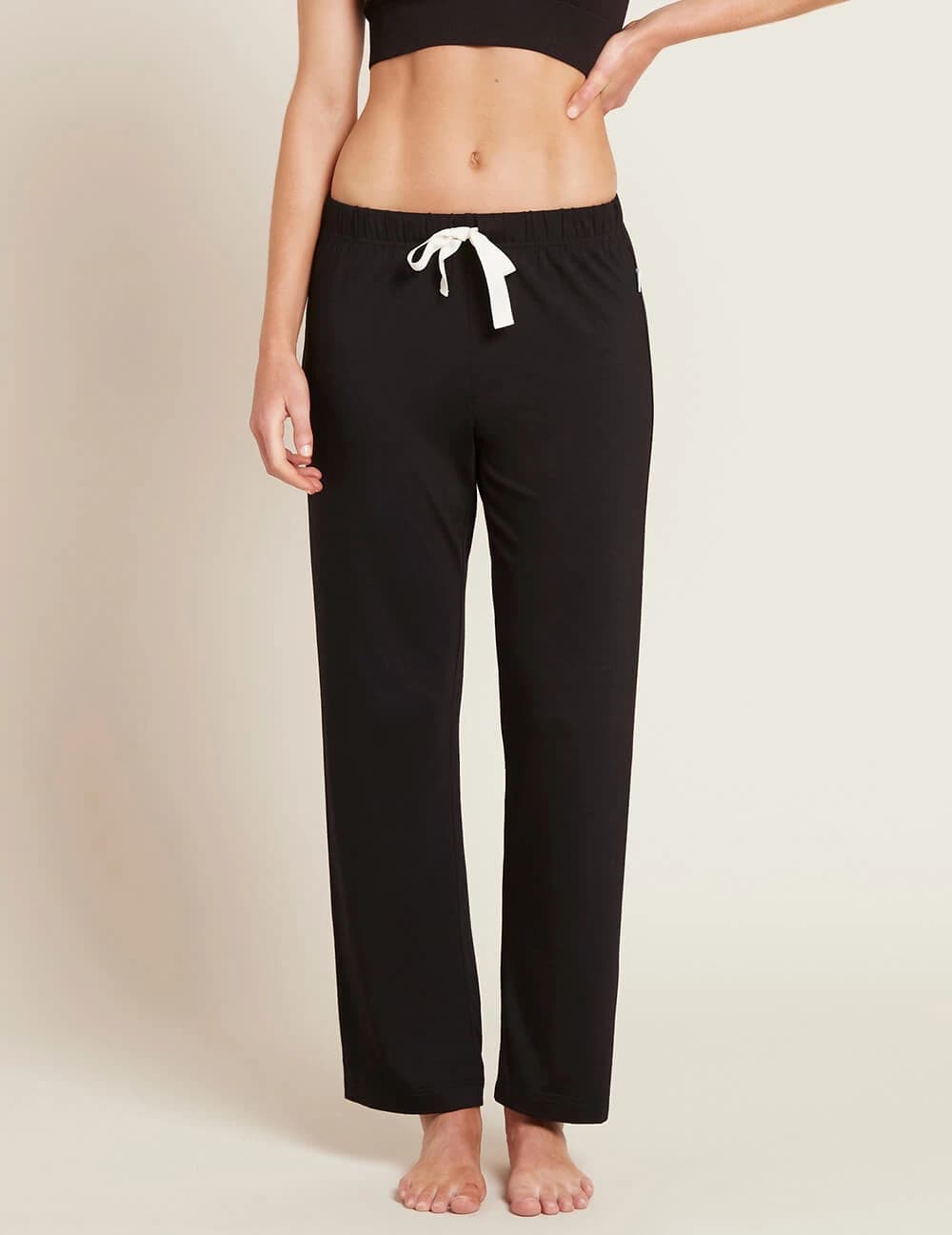 Black lounge pants with a white drawstring on a beige background