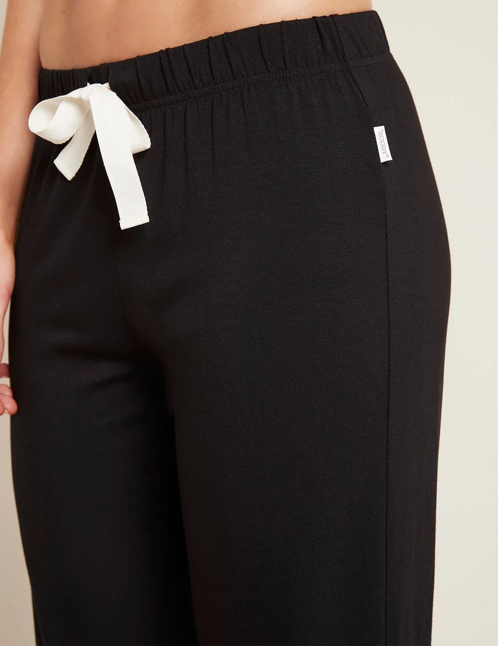 Black pants with a white bow detail on a neutral background