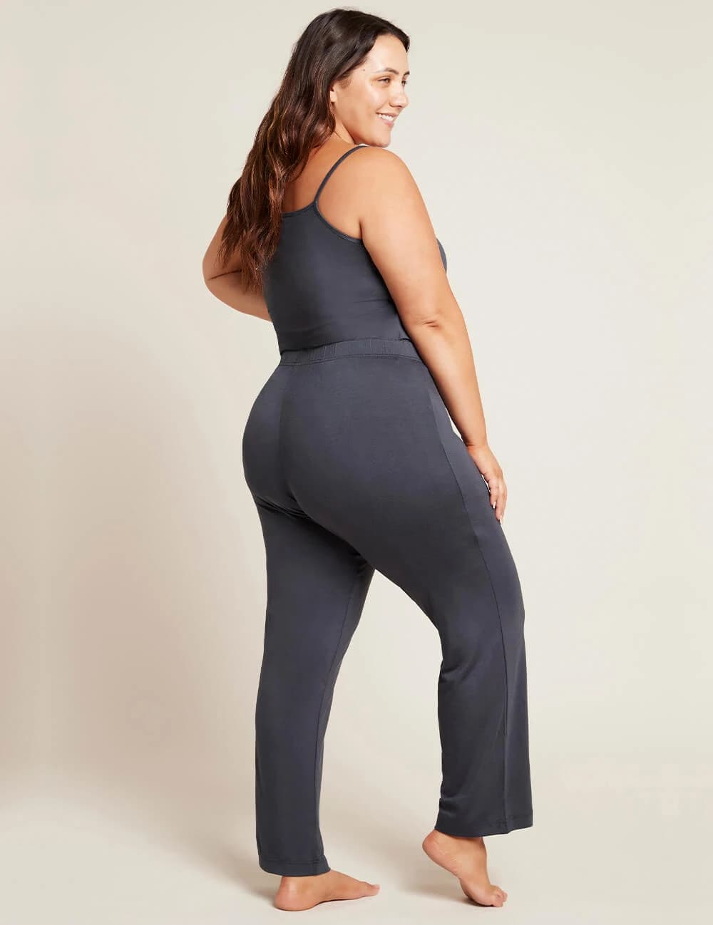 Woman wearing a dark gray jumpsuit against a plain background