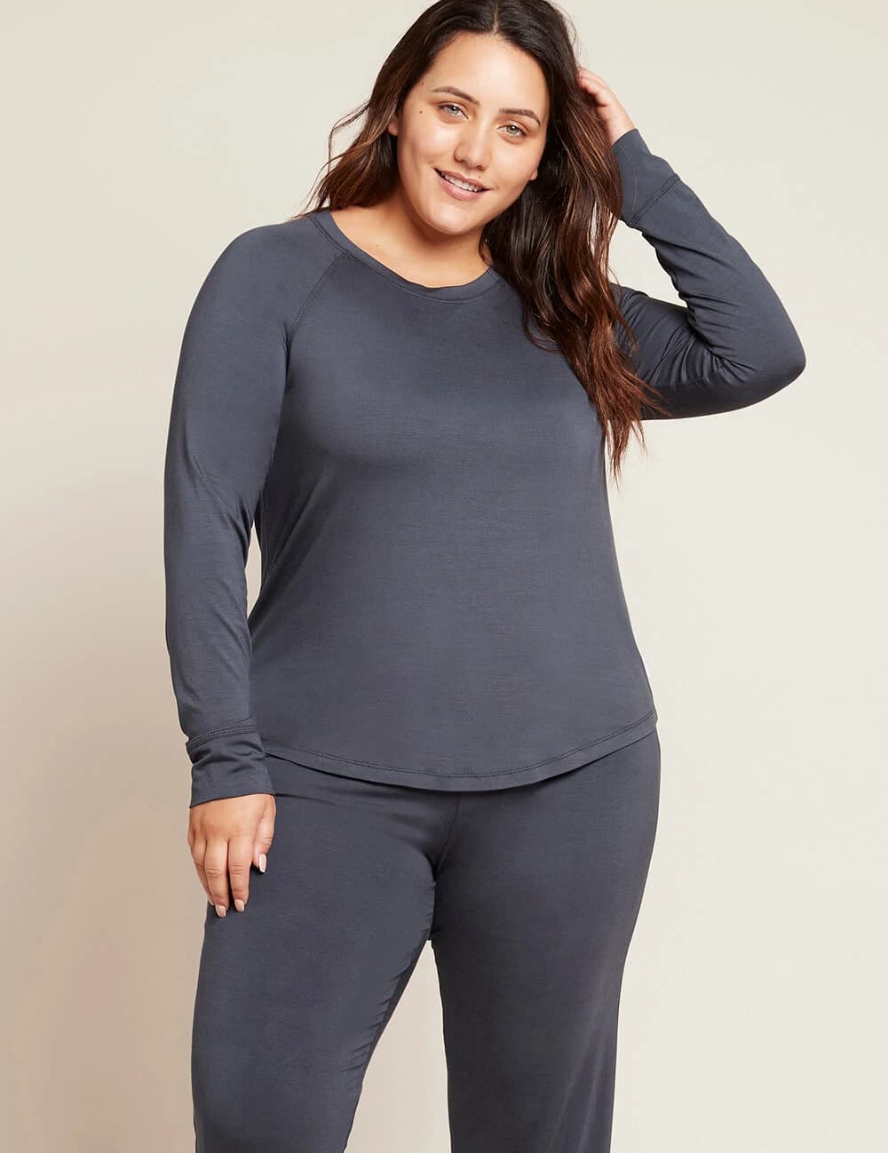 Woman wearing a gray long-sleeve top and pants on a beige background