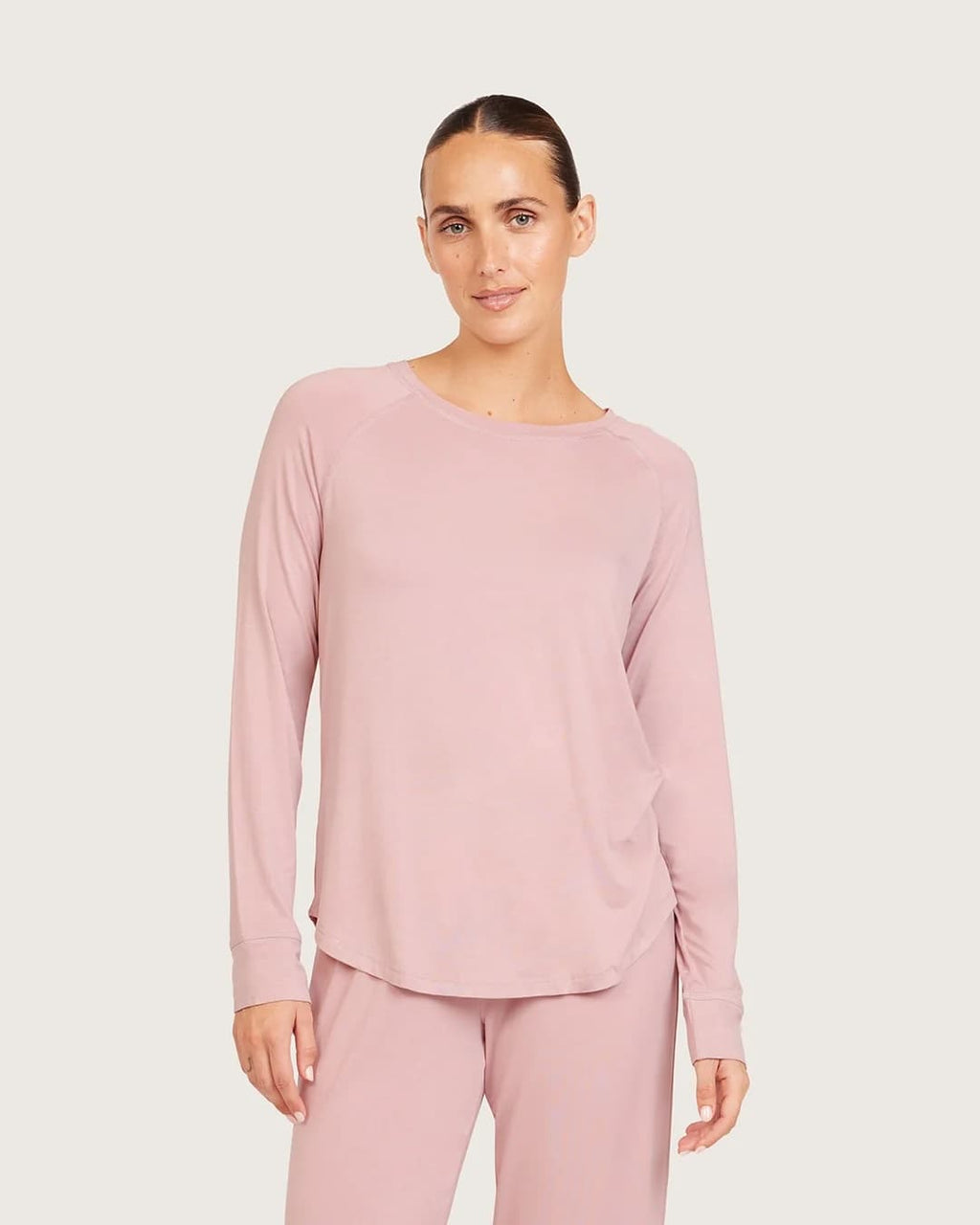 A woman modeling a dusty lilac long-sleeve top and matching pants against a light gray studio background.