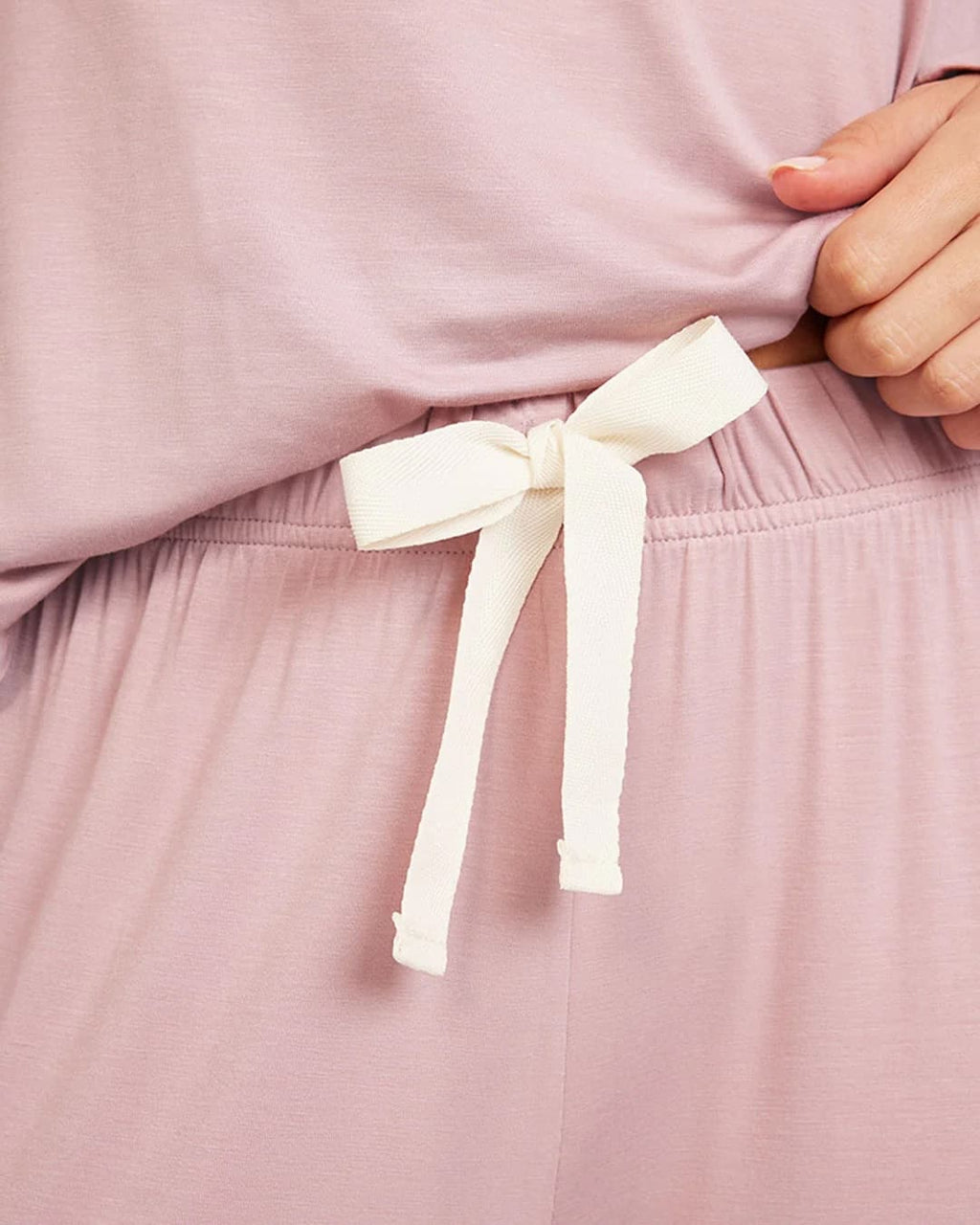 Close-up of a lilac pant with a white ribbon tie, held by a hand.