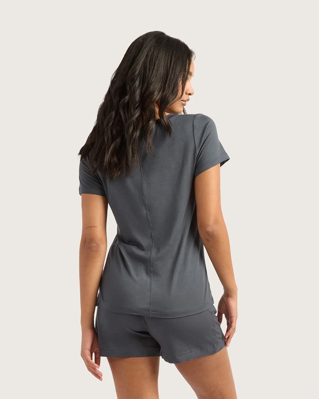 Woman wearing a gray athletic outfit on a plain background