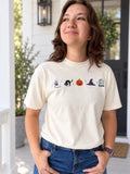 woman in cream colored tee shirt with halloween icons across the chest.