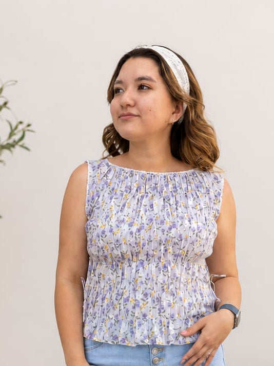 Woman wearing a floral top and light blue jeans standing in a living room.