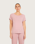 Woman wearing a pink top and pants on a plain background