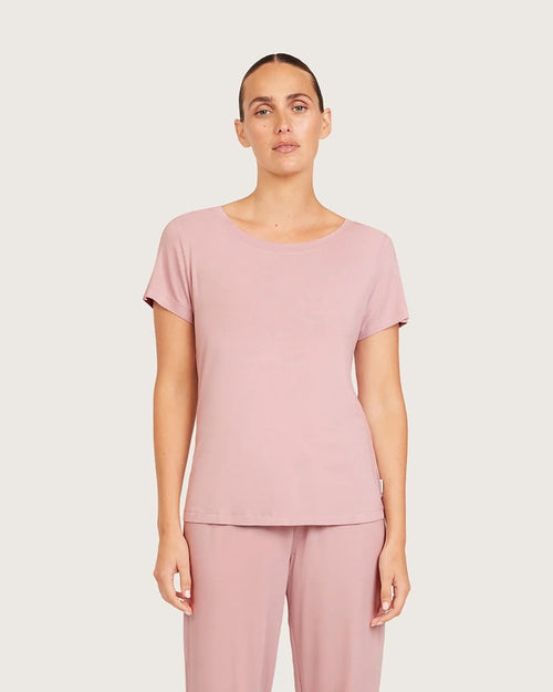 Woman wearing a pink top and pants on a plain background