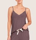A woman wearing a dark grayish-brown camisole top with thin straps and a small cream tie detail at the waist, shown against a plain light background.