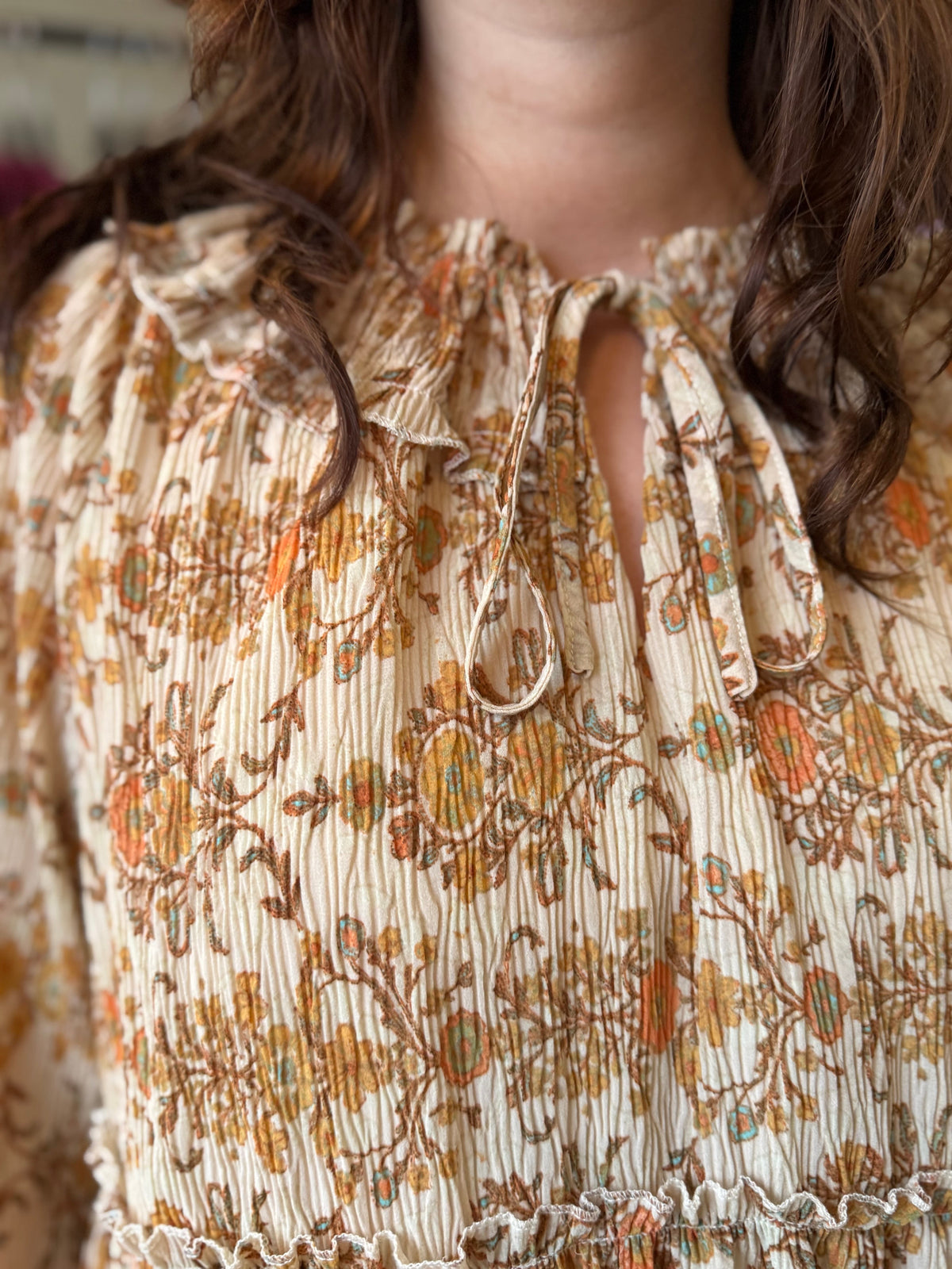 Close up of the neckline of a woman wearing printed boho style peasant blouse top in beautiful orange and tan colors.