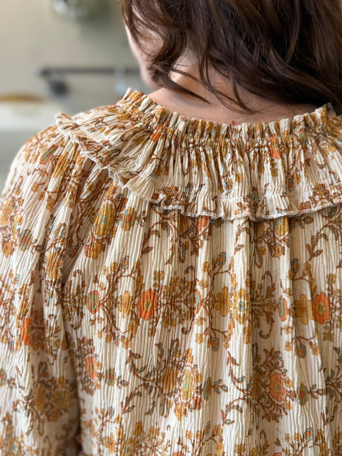 Close up back view of a woman wearing printed boho style peasant blouse top in beautiful orange and tan colors.