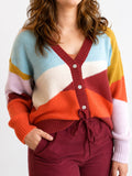A woman wearing a fuzzy color-block cardigan sweater with a V-neck, button front, and ribbed cuffs and hem, paired with burgundy drawstring pants against a plain light background.