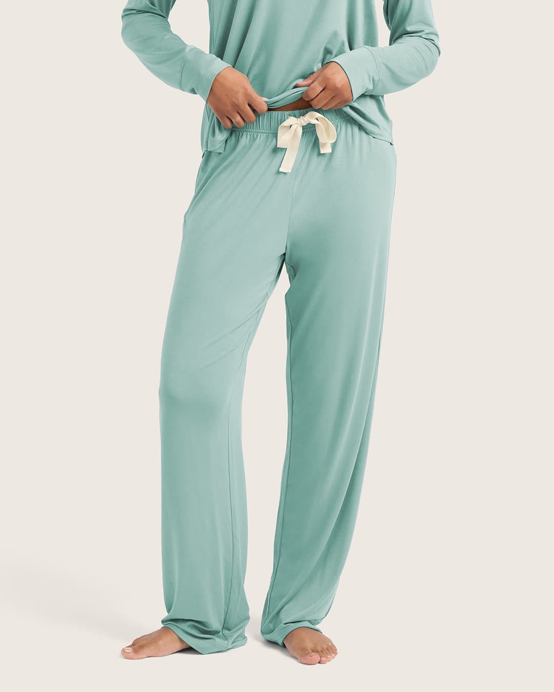 Person wearing a mint green pajama set on a white background