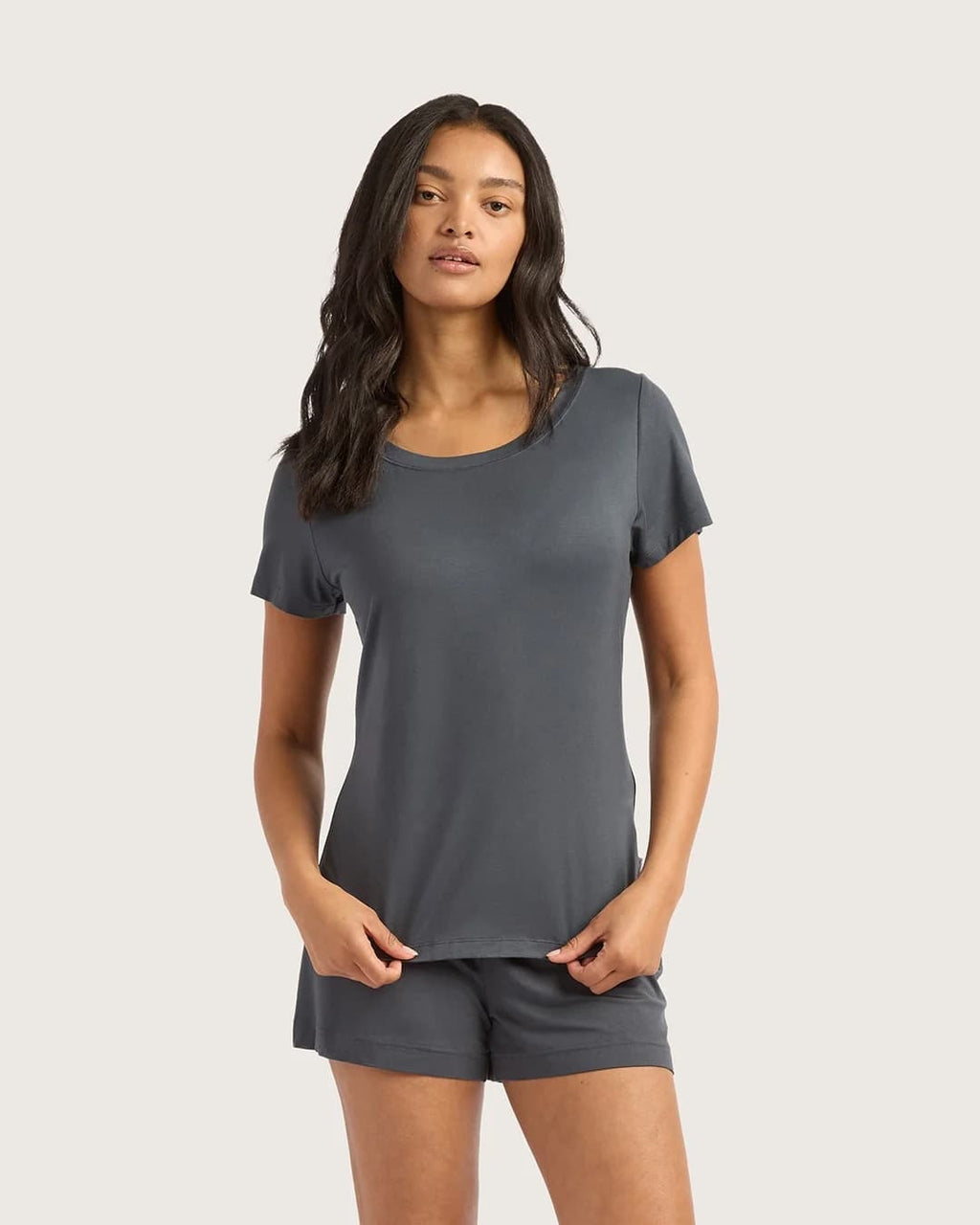 Woman wearing a gray t-shirt and shorts set on a plain background
