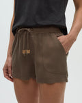 Person wearing brown tencel shorts with drawstring on a white background