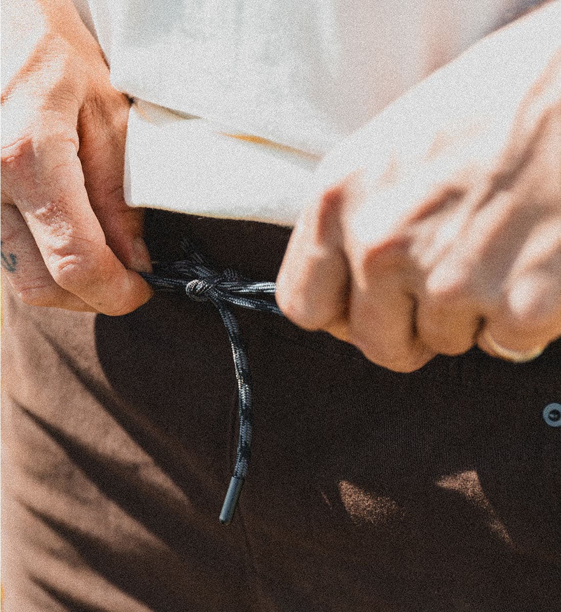 Close-up of hands tying a drawstring waistband.